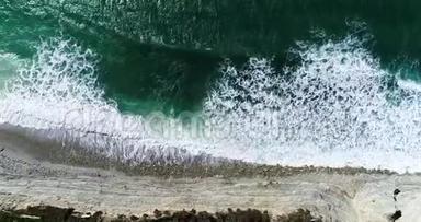 海浪与白色泡沫翻滚在一个高岩石岸下的一个<strong>摇摇欲坠</strong>的海滩。 从宝座上俯瞰