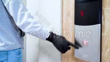 在冠状病毒和<strong>传染病</strong>流行期间，一个戴着黑色防护手套的人按下电梯按钮。