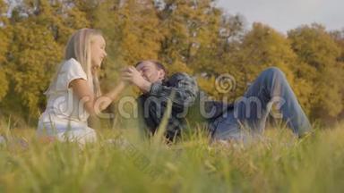 父亲和女儿坐在秋天的草地上为苹果而战。 白人男子和年轻的金发女孩
