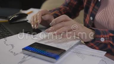 特写女人正在计算器上数数字。 在隔离期间在家工作。