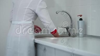 医院一名医务人员擦拭洗手池和水龙头，然后擦拭桌子表面。