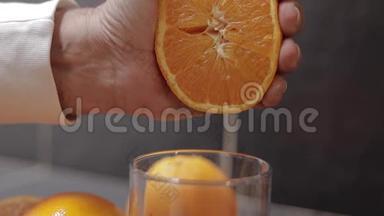男人的手把橘子汁挤到玻璃杯里. 男人手里拿着一半的橘子