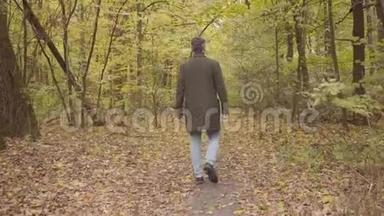 一个白人成年人在森林里走的背影。 一个穿着便服的人，享受宁静的秋日