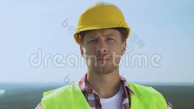 有经验的男建筑工人戴着安全帽看相机，提供优质服务