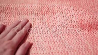 女孩`手触摸一件柔软温暖的丙烯酸或珊瑚色或粉红色的羊毛毛衣。