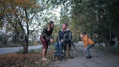 与一家残疾男子在轮椅上休息，一个幸福的妻子带着孩子在公园里与<strong>残疾人</strong>玩耍