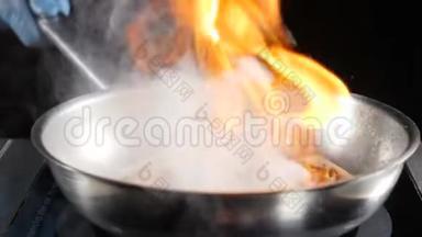 不可辨认的厨师把热的不粘<strong>煎</strong>锅与<strong>海鲜</strong>，然后点燃它烹饪火焰菜。 慢慢