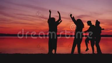 快乐的朋友在黑暗中的海滩上跳<strong>舞</strong>，<strong>背景</strong>是日落