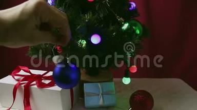 那个年轻女孩`手把一个蓝色的球挂在圣诞树上。 女孩装饰圣诞树.