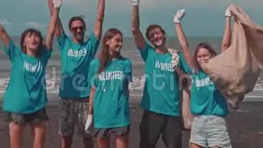 身穿蓝色生态T<strong>恤衫</strong>的志愿者庆祝海滩垃圾的胜利