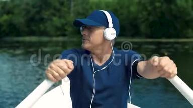 一个<strong>头发</strong>花白、戴着白耳机、戴着蓝帽子、穿着t恤、戴着眼镜的<strong>男子</strong>在白船上划桨