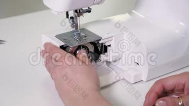 女士在缝纫机中放置带线的<strong>穿梭</strong>机准备工作，双手特写。