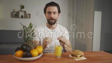 年轻人坐在一张<strong>桌子上</strong>，在一盘<strong>水果</strong>、果汁和汉堡包<strong>上</strong>，一个人正在枯萎有用的产品。