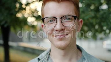 英俊的红头发男子的特写肖像，脸上有雀斑，在户外微笑