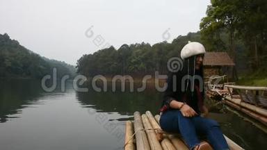泰国女游客参观泰国梅洪山庞恩湖上的竹筏，坐在那里放松