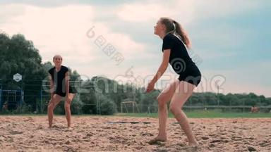 参加职业沙滩排球比赛的妇女。 一名后卫试图阻止两名女子的射击