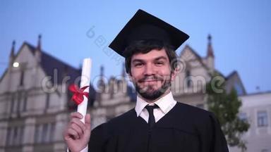 白人快乐的年轻人<strong>毕业了</strong>，对着镜头摆姿势，在大学门口展示他的文凭。