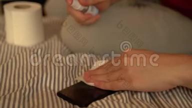 人手在手机上喷洒酒精消毒液，防止感染Covid-19病毒.. 冠状病毒污染