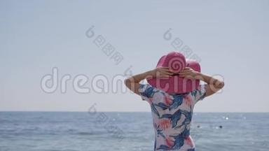 孤独优雅的女人，穿着蓝色的泳衣，粉<strong>红色</strong>的帽子，站在<strong>海边</strong>，看着地平线