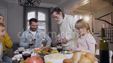 在节日的家庭聚餐中，尊敬的老人把烤火鸡放在盘子里