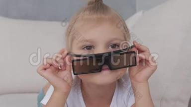 一个戴3D眼镜的小女孩专注地看着电视<strong>屏</strong>幕。