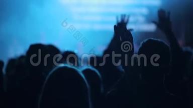 人们在音乐会上举手. 特写镜头。 后景。 唱歌。 模糊的阶段。