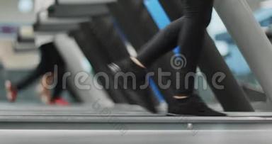 年轻女子在健身房跑步机上行走。 热身或<strong>降温</strong>.. 腿侧视近景拍摄，下身细节.. 妇女