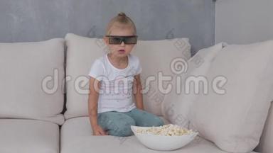 一个小女孩在柔软的沙发上吃爆米花，看着3D眼镜里的电视<strong>屏</strong>幕。
