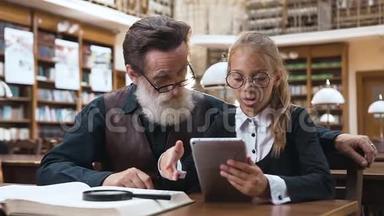 可爱的小女孩戴眼镜阅读故事从电子书到她聪明的大胡子爷爷在图书馆