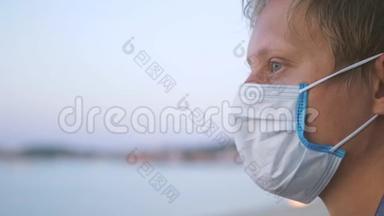 戴着医用面具的年轻人在海滩上沉思。 冠状病毒流行