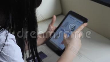 女孩用数字平板电脑制作网上购物概念。 黑发女人躺在沙发上看网上商店的生活方式