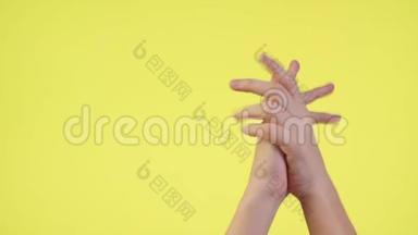 女人的双手交叉着手指，等待着特殊的时刻，让愿望在黄色的背景上被隔离