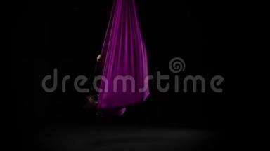 女子空中体操运动员在马戏团舞台上表演紫罗兰丝绸。 精彩的杂技表演