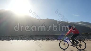 一个年轻人骑着自行车在加那利群岛的沙滩上，在美丽的日出灯光下骑着一辆自行车，骑着神奇的山