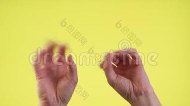 女人的手挥动着，跳舞的手指拍打着音乐节奏的手势，在工作室里的黄色背景上被隔离开来。