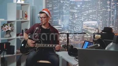 家庭录音室：戴着圣诞帽的年轻歌手用麦克风和吉他唱圣诞歌曲