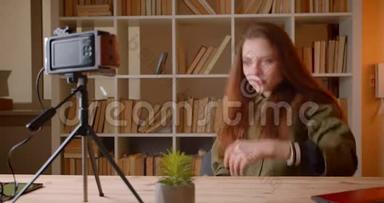 女青少年博客设置了<strong>视频</strong>摄像头，并<strong>开始</strong>热情地在书架背景上交谈。
