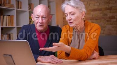 两位白发苍苍的白种人高级<strong>配偶</strong>在笔记本电脑上用视频聊天的特写镜头积极地打手势
