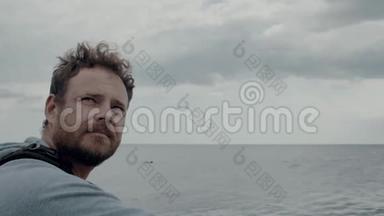 一个留胡子的人在海和云的<strong>背景</strong>下的肖像，用相机拍摄<strong>大海</strong>的照片。 4k. 4k视频