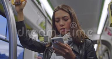 可爱的黑发女人的肖像抓住扶手，在<strong>公共交通工具</strong>上发短信和浏览手机。 城市