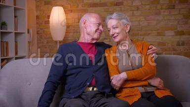 高白种人的配偶坐在沙发上互<strong>相拥</strong>抱，在家里既快乐又温柔。