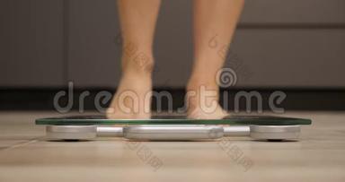 女人踩着秤。 女足检查厨房的体重。 测量体重的人腿，近距离观看