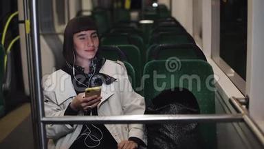 年轻时尚的女士戴着耳机听音乐，在<strong>公共交通工具</strong>上浏览手机。 城市