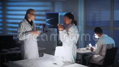 穿着<strong>白大褂</strong>的混合种族女工程师在讨论现代实验室的事情