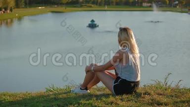 苗条的女孩坐在山上，看着美丽的欧洲风格城市美丽的图画景观和美丽的湖泊