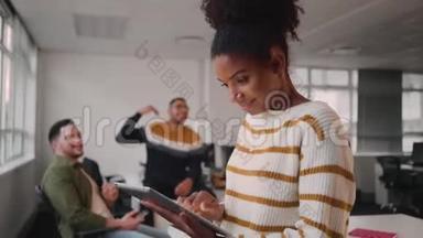 同事在办公室后台互动时，用数码平板电脑微笑年轻的非洲女商人