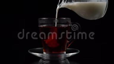 在黑茶中，在<strong>玻璃</strong>茶杯和茶碟中倒入牛奶，从<strong>玻璃壶</strong>中倒入黑色背景，慢镜头拍摄