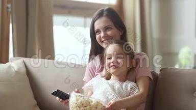 妈妈拿着遥控器和小女儿一起看电视