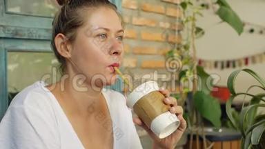 年轻的女人喝鸡尾酒，用吸管和微笑排毒冰沙。 一个喜欢清新的女孩的肖像