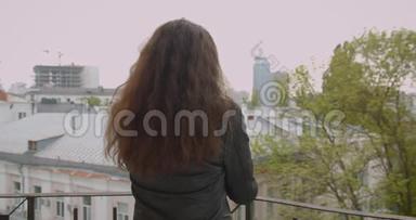<strong>阳台</strong>上穿着皮夹克的黑发女孩坐在<strong>阳台</strong>上，欣赏着都市的景色，后镜头转向镜头，开心地微笑着。